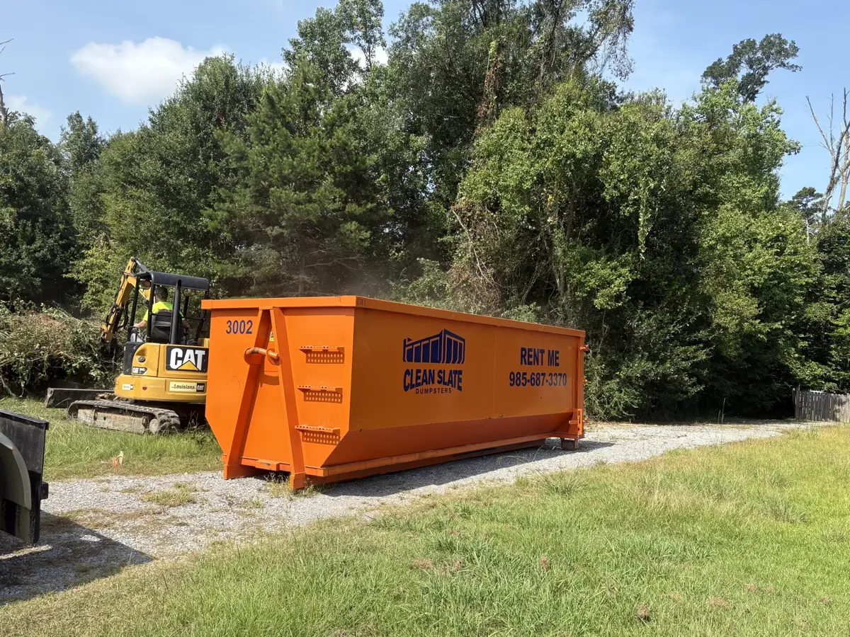 cat excavator loading dumpster debris