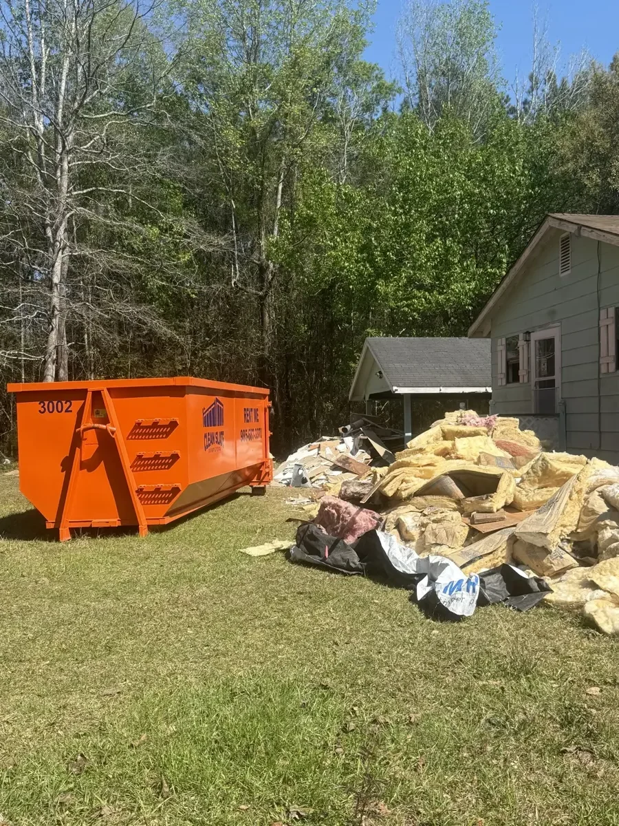 Roll-off dumpster filled with torn-off shingles during a residential roof tear-off