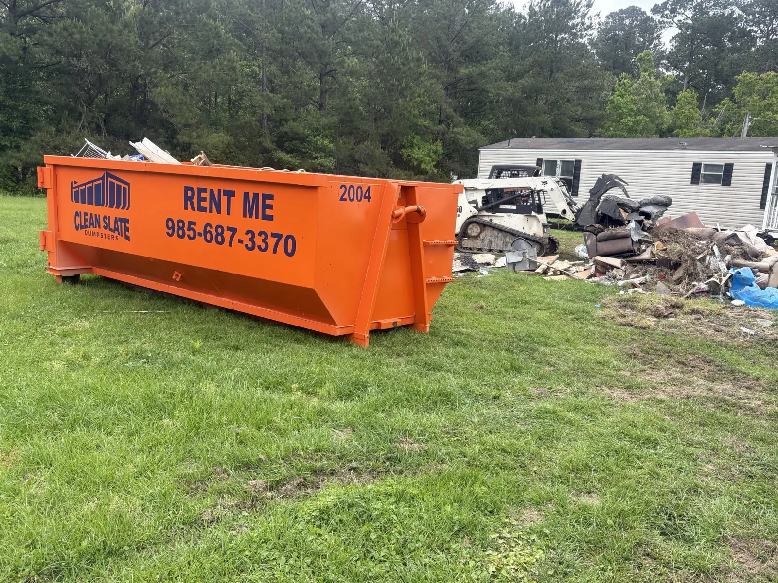 Clean Slate Dumpsters 20-yard Load and Go dumpster on a property cleanout in Hammond, LA with debris staged for loading